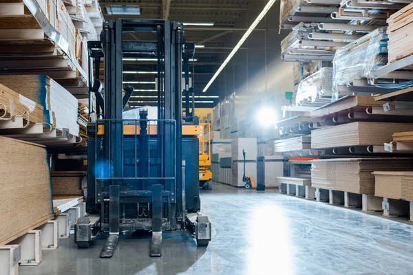 Forklift machine in warehouse near shelves with wooden construction materials — Stock Photo