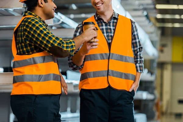 Fröhliche multikulturelle Arbeiter, die im Lager mit Pappbechern klappern — Stockfoto