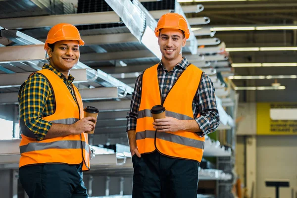 Fröhliche multikulturelle Arbeiter, die Pappbecher in der Hand halten und in die Kamera schauen — Stockfoto