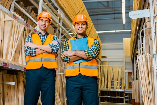 Cheerful multicultural workers with crossed arms smiling and looking at camera — Stock Photo