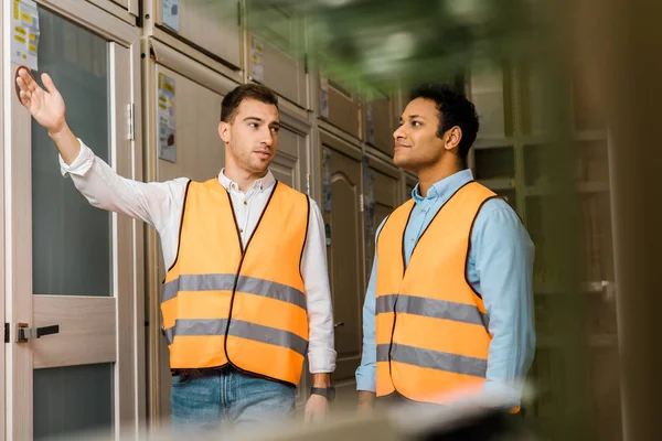 Selective focus of multicultural workers talking while standing in doors department — Stock Photo