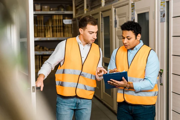 Focus selettivo del magazziniere indiano che scrive negli appunti vicino al collega — Foto stock