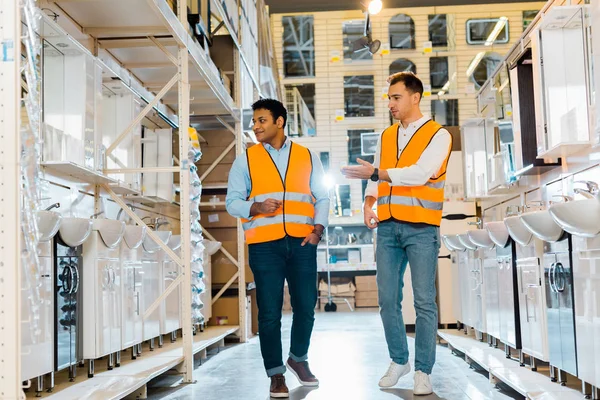 Smiling multicultural workers in safety vests talking in plumbing department — Stock Photo