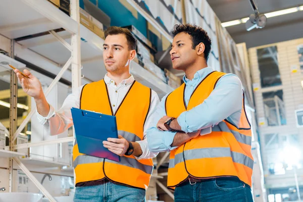 Attentive multicultural warehouse workers in safety vests working in plumbing department — Stock Photo