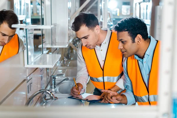 Selective focus of attentive multicultural colleagues working in plumbing department — Stock Photo