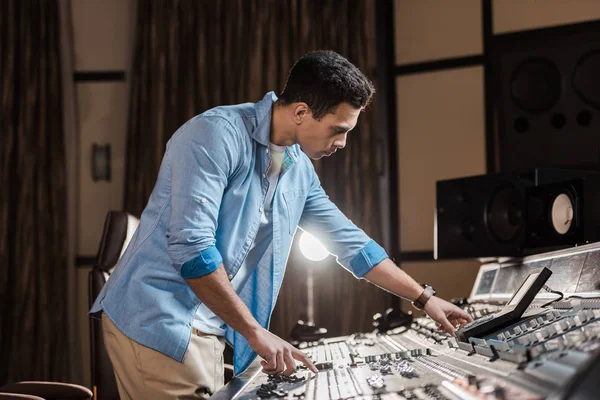 Produtor de som concentrado trabalhando no console de mixagem em estúdio de gravação — Fotografia de Stock