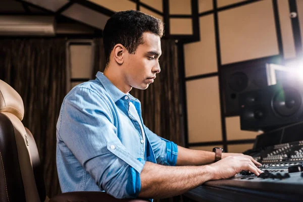 Concentrated mixed race sound producer working at mixing console in recording studio — Stock Photo