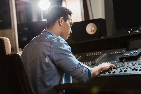 Concentrated mixed race sound producer working at mixing console — Stock Photo