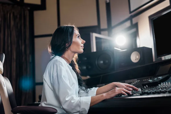 Attractive sound producer working at mixing console in recording studio — Stock Photo