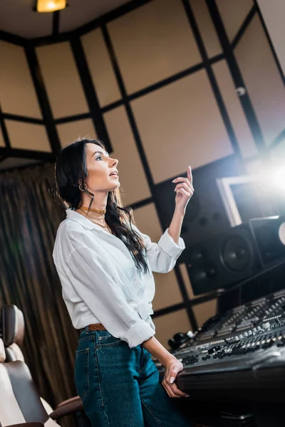 Produtor de som atencioso gesticulando enquanto trabalhava no console de mixagem em estúdio de gravação — Fotografia de Stock