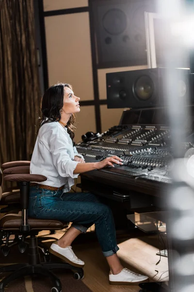 Selective focus of attractive sound producer working at mixing console in recording studio — Stock Photo