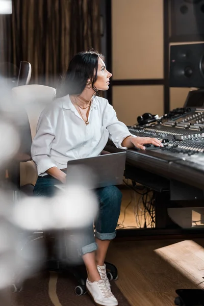 Selective focus of attractive sound producer with laptop working at mixing console — Stock Photo