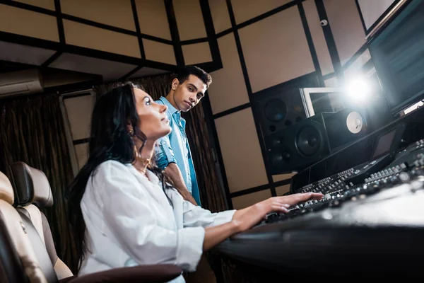 Young multicultural sound producers working at sound console in recording studio — Stock Photo