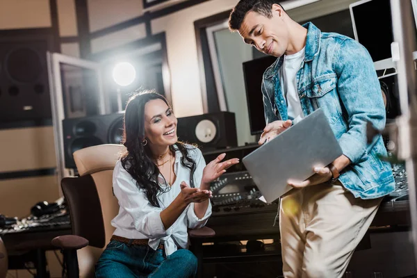 Mixed Race Soundproduzent mit Laptop neben hübsch lächelndem Kollegen — Stockfoto