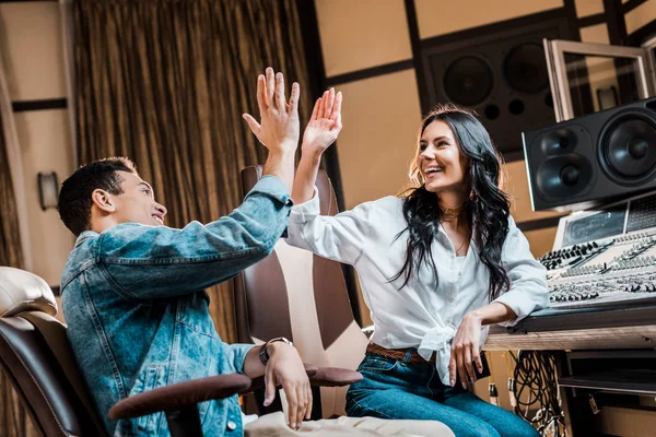 Dos productores de sonido alegre multicultural dando cinco en el estudio de grabación - foto de stock