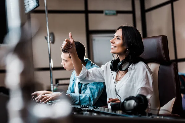 Selektiver Fokus eines hübschen Soundproduzenten in Kopfhörern, der am Mischpult in der Nähe eines Mischlingsfreundes arbeitet — Stockfoto