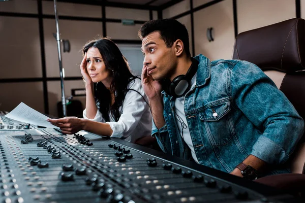 Dois produtores de som pensativos trabalhando no console de mixagem em estúdio de gravação — Fotografia de Stock