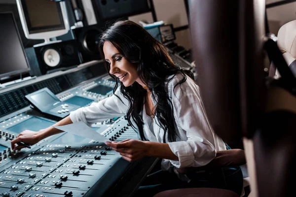 Attractive smiling sound producer working at mixing console in recording studio — Stock Photo