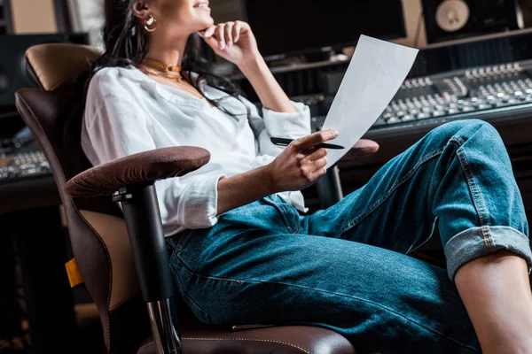 Vista parcial del productor de sonido sentado en la silla de la oficina cerca de la consola de mezcla — Stock Photo