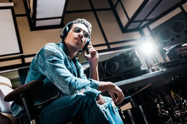 Beau, métis, producteur de son concentré dans les écouteurs écoutant de la musique en studio d'enregistrement — Photo de stock