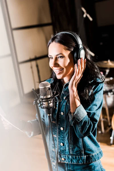 Вибірковий фокус натхненної жінки в навушниках, що співають у студії звукозапису — стокове фото