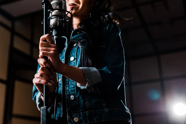 Partial view of woman singing near microphone in recording studio — Stock Photo