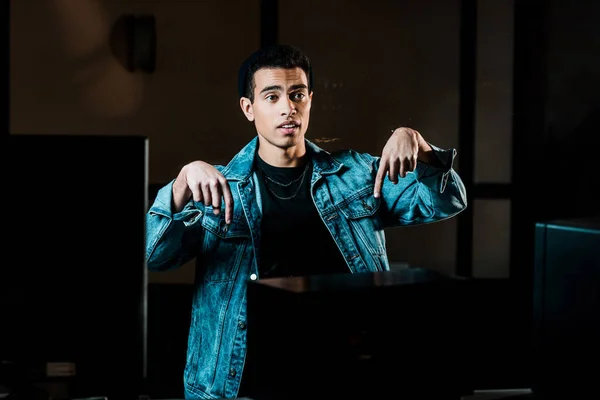 Handsome mixed race sound producer gesturing in dark recording studio — Stock Photo