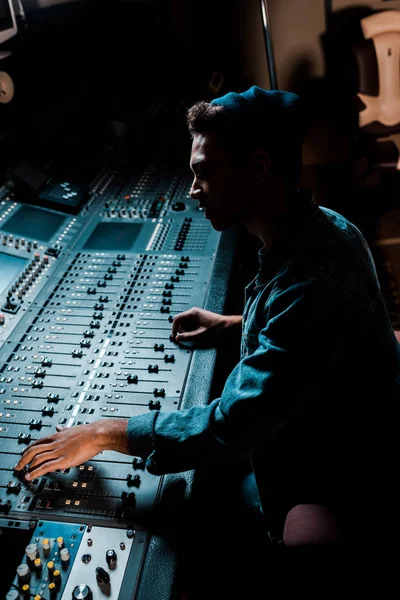 Sound producer working at mixing console in dark recording studio — Stock Photo