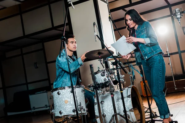 Pretty singer and handsome mixed race drummer talking in recording studio — Stock Photo