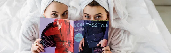 Panoramic shot of women with towels on heads hiding behind magazine in bed — Stock Photo