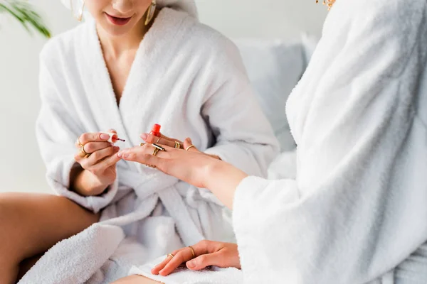 Vue recadrée de femme en peignoir de polissage des ongles à un ami — Photo de stock