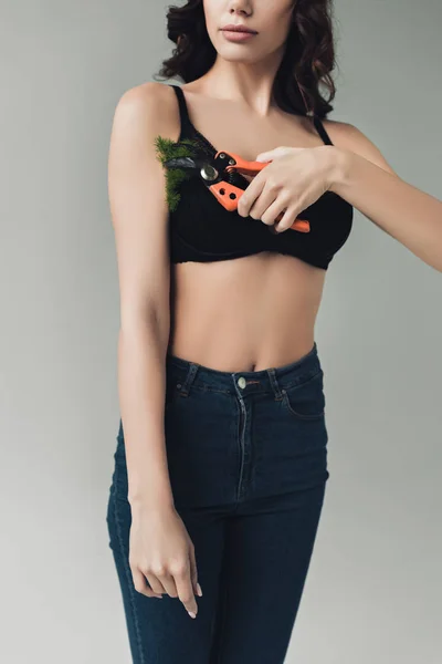 Cropped view of woman in black bra cutting plant on armpit with secateurs isolated on grey — Stock Photo