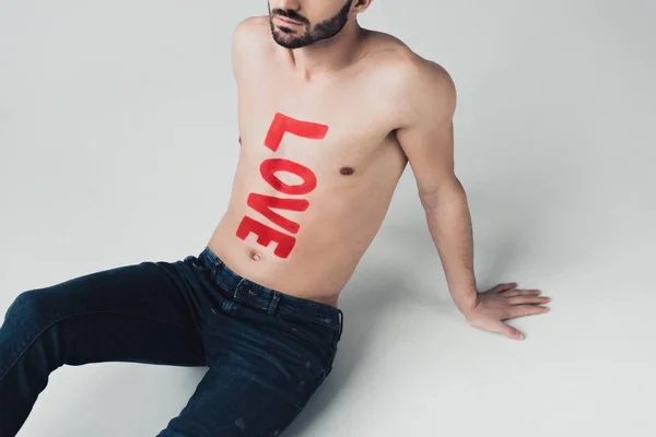 Vista ritagliata di uomo senza camicia con iscrizione sul corpo seduto sul grigio — Foto stock