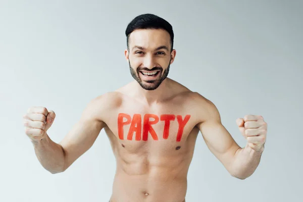 Hombre sin camisa sonriente con inscripción en el cuerpo mostrando sí gesto en gris - foto de stock