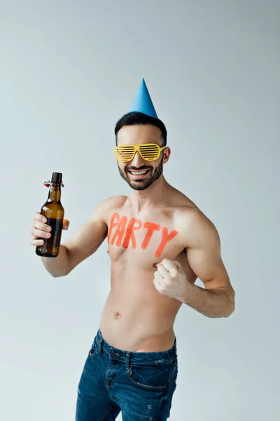 Homme souriant dans des lunettes et chapeau de fête tenant de la bière et regardant la caméra isolée sur gris — Photo de stock