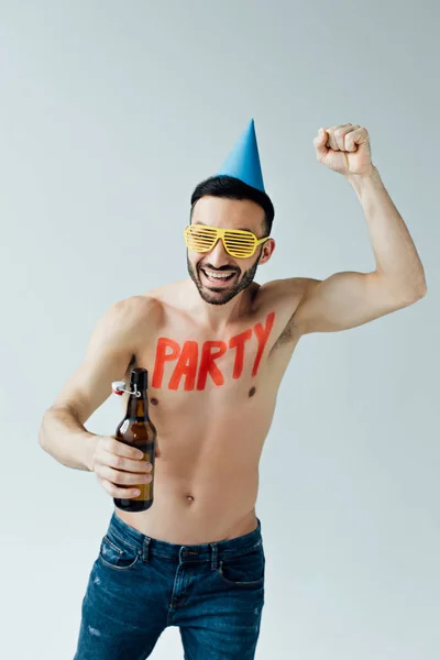 Lachender, hemdloser Mann mit Partyhut, Bier in der Hand und Ja-Geste isoliert auf grau — Stockfoto