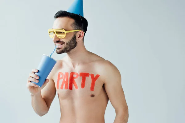 Hombre sin camisa en sombrero de fiesta con inscripción en el cuerpo bebida aislada en gris - foto de stock