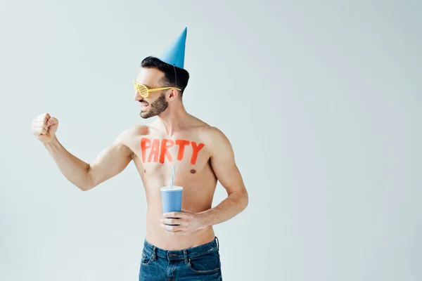 Мужчина без рубашки с надписью на теле держит напиток и показывает да жест изолирован на сером — стоковое фото