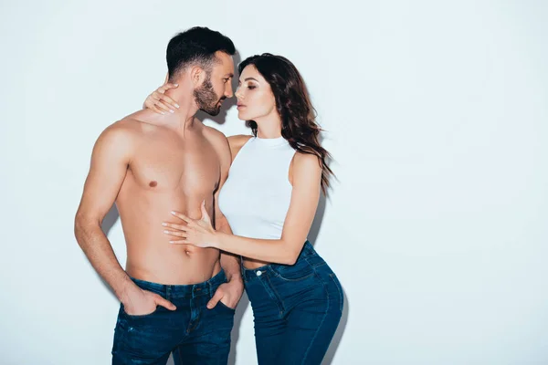 Pretty young woman embracing shirtless boyfriend on grey — Stock Photo