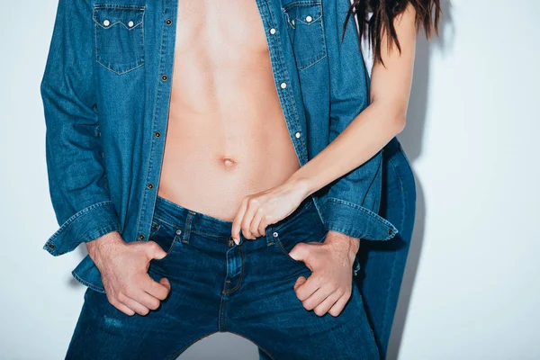 Частичный вид пары в джинсах, стоящей вместе на сером — стоковое фото
