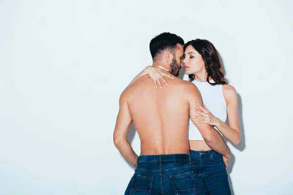 Pretty young woman embracing shirtless boyfriend on grey — Stock Photo