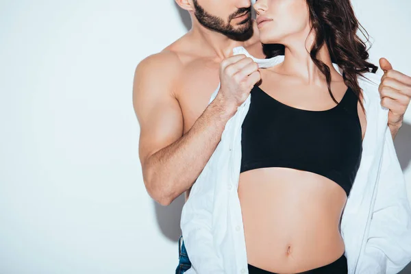 Cropped view of bearded man undressing girlfriend on grey — Stock Photo