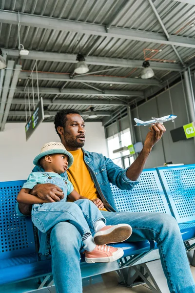 Africano americano padre e hijo jugando con juguete avión en aeropuerto - foto de stock