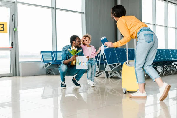 Посміхаючись афроамериканець батько і дочка зустріч матері і дружини з багажем в аеропорту — стокове фото