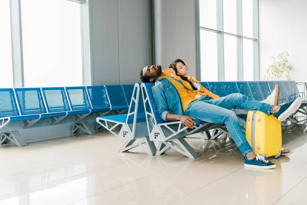 Pareja afroamericana cansada durmiendo en la sala de salida en el aeropuerto - foto de stock