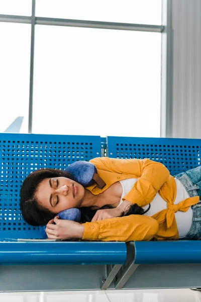 African american woman sleeping on seats with travel pillow in departure lounge — Stock Photo