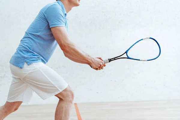 Cropped view of sportsman in blue polo shirt playing squash in sports center — Stock Photo