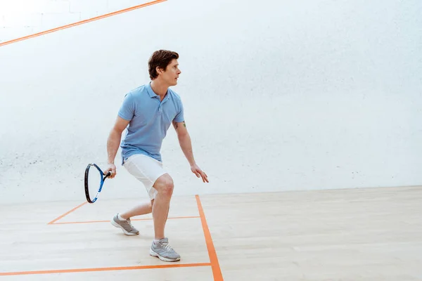 Concentrated sportsman in blue polo shirt playing squash in sports center — Stock Photo