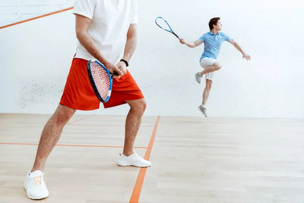 Vista parziale di due giocatori di squash con racchette in campo a quattro pareti — Foto stock