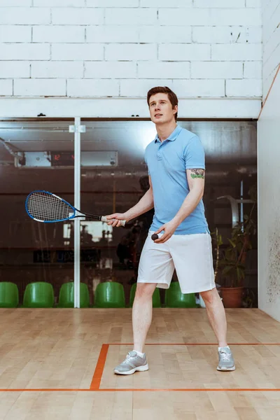 Visão de comprimento total do desportista em camisa de pólo azul jogando squash em quadra de quatro paredes — Fotografia de Stock